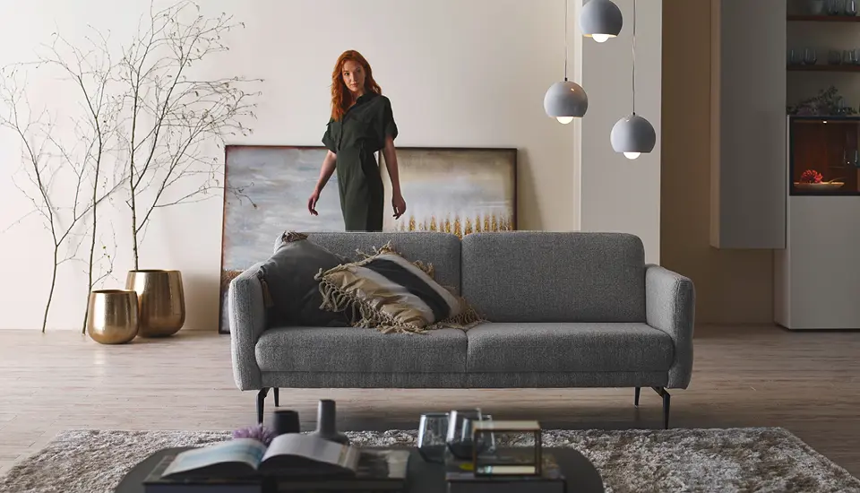 Esszimmer mit Holztisch, sechs gepolsterten Stühlen und Kaminwand aus Naturstein; großer Fensterbereich, Holzfußboden und ein Mann, der lässig danebensteht.